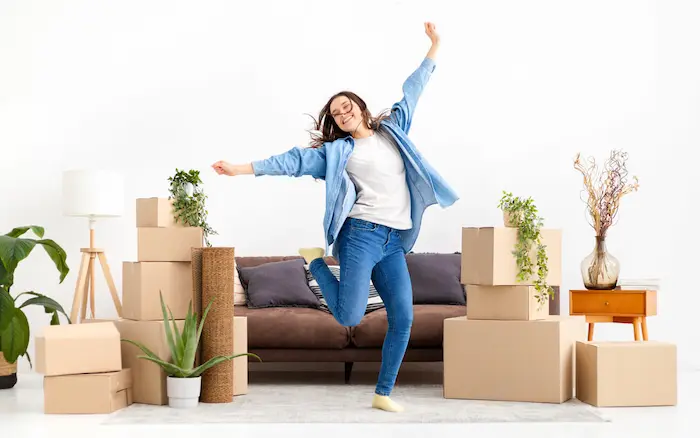 Photo d'une étudiante qui saute en l'air, ravie d'emménager dans son nouveau logement étudiant en France. Elle va pouvoir réduire ses charges grâce à l'APL étudiant 2025.