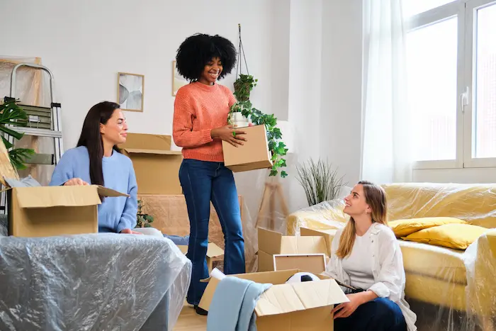 Trois étudiantes souriantes se trouvent au milieu de plusieurs cartons. Elles viennent d'emménager dans un appartement étudiant. Elles se sont demandé quel type de logement choisir selon son budget et ont opté pour la colocation.