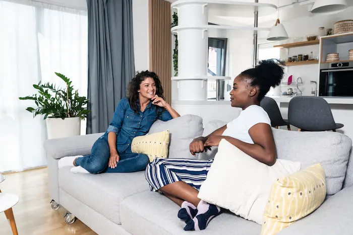 Deux étudiantes souriantes, assises dans leur salon en colocation à Rennes.
