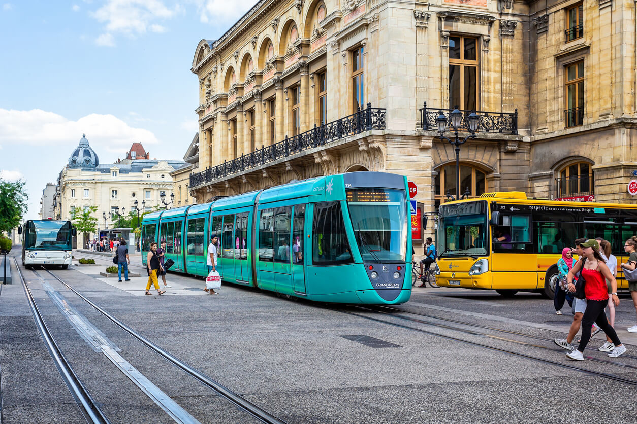 Photo d'un tramway et de bus dans la ville de Reims. Elle met en avant le réseau de transport vaste de la ville, notamment autour d'une résidence étudiante à Reims