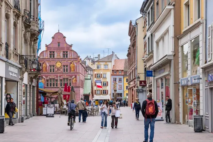 Le centre-ville de Mulhouse, mettant en valeur le charme de cette ville. L'on voit des passants, des boutiques et des immeubles abritant des logements étudiants à Mulhouse.