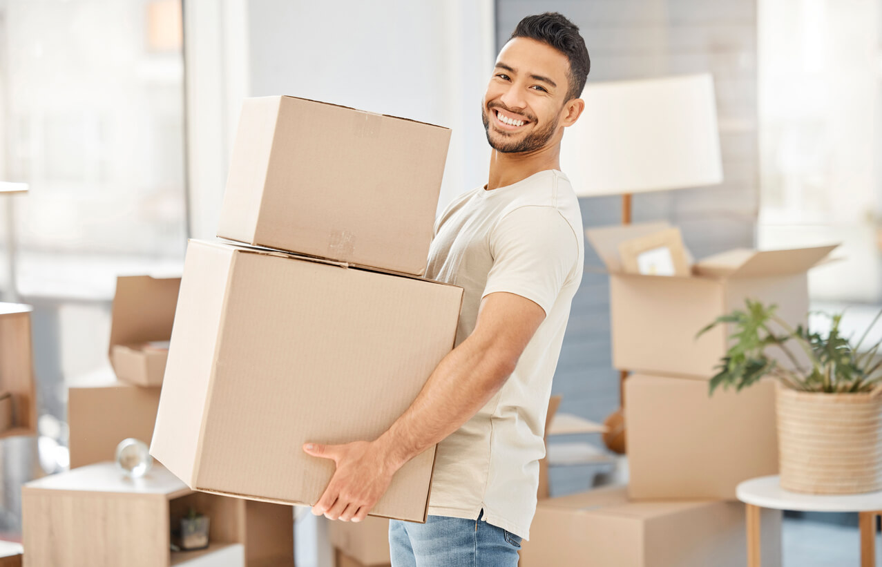 Un jeune étudiant transportant des cartons. Il est très souriant, heureux d'emménager dans son logement en résidence étudiante à Paris 20