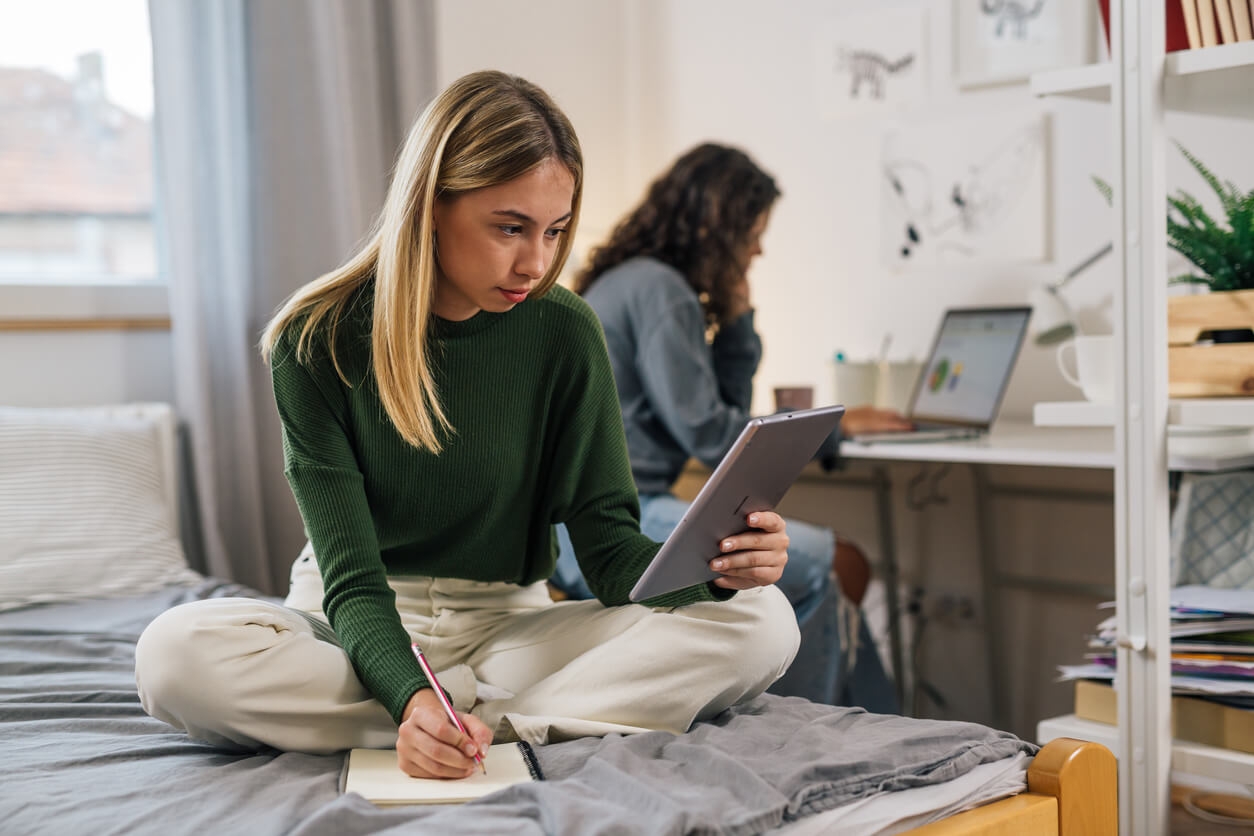 Deux étudiantes dans une résidence étudiante Rennes, l'une étudiant sur son lit, et l'autre en arrière-plan travaille sur son ordinateur posé sur la table 