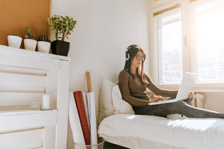 résidence étudiante à Bordeaux : une étudiante est en train de réviser ses cours sur son lit depuis un ordinateur. Elle est dans une résidence étudiante avec des services inclus.