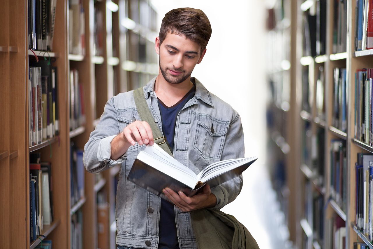 Jeune étudiant dans le couloir d'une bibliothèque, semblable à celle d'une résidence étudiante à Paris 19