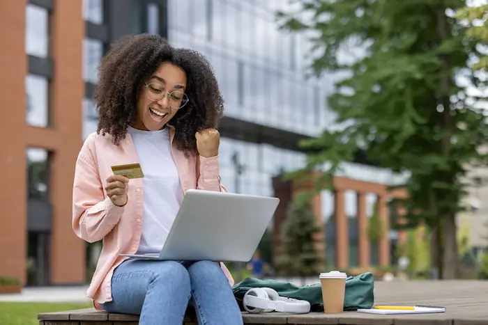 Une étudiante heureuse, assise dans un jardin, ravie d'avoir trouvé un logement étudiant Palaiseau adapté à son budget